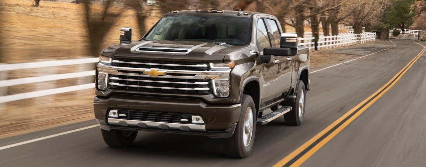 A brown 2020 Chevy Silverado 2500HD High Country is shown driving on a highway.