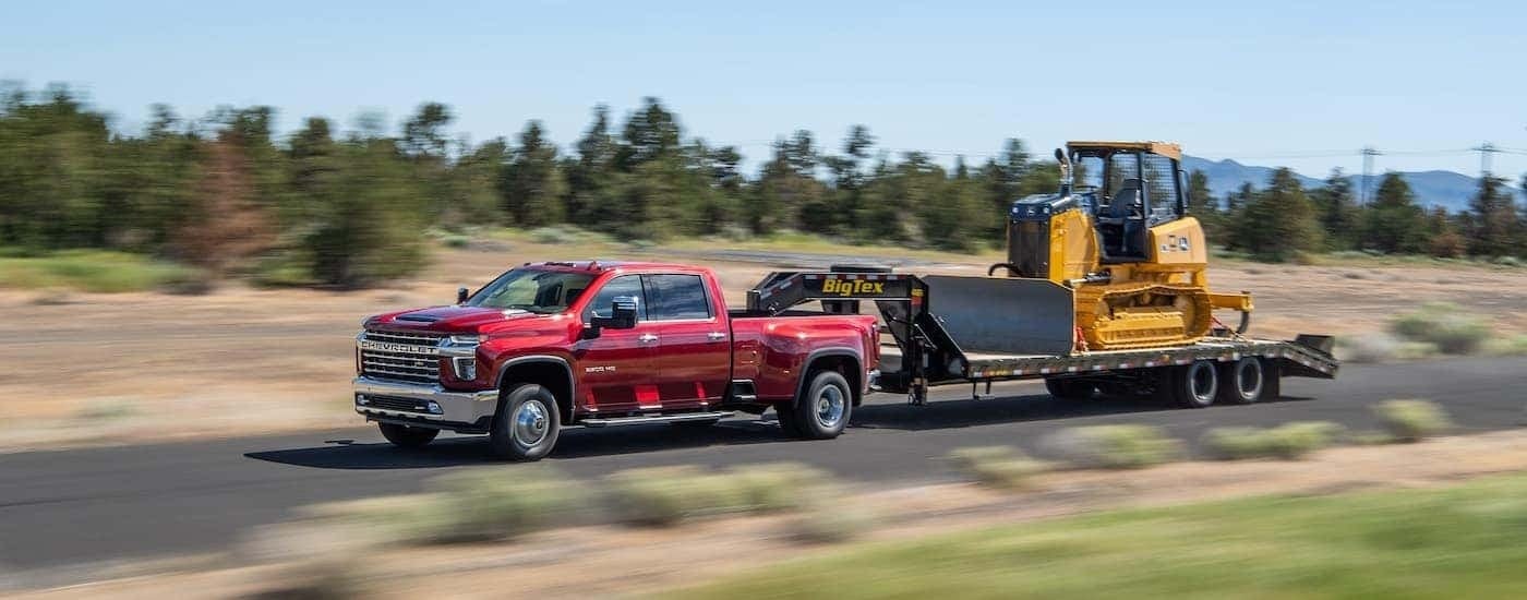 A red 2022 Chevy Silverado 3500 HD is shown towing a bulldozer.