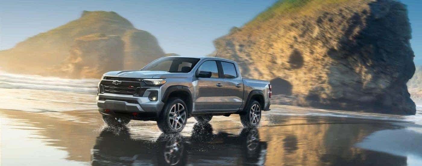 A silver 2024 Chevy Colorado Z71 is shown driving near an ocean.