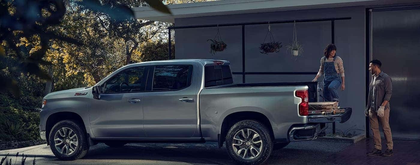 A silver 2024 Chevy Silverado 1500 Z71 is parked in a driveway being loaded with boards.