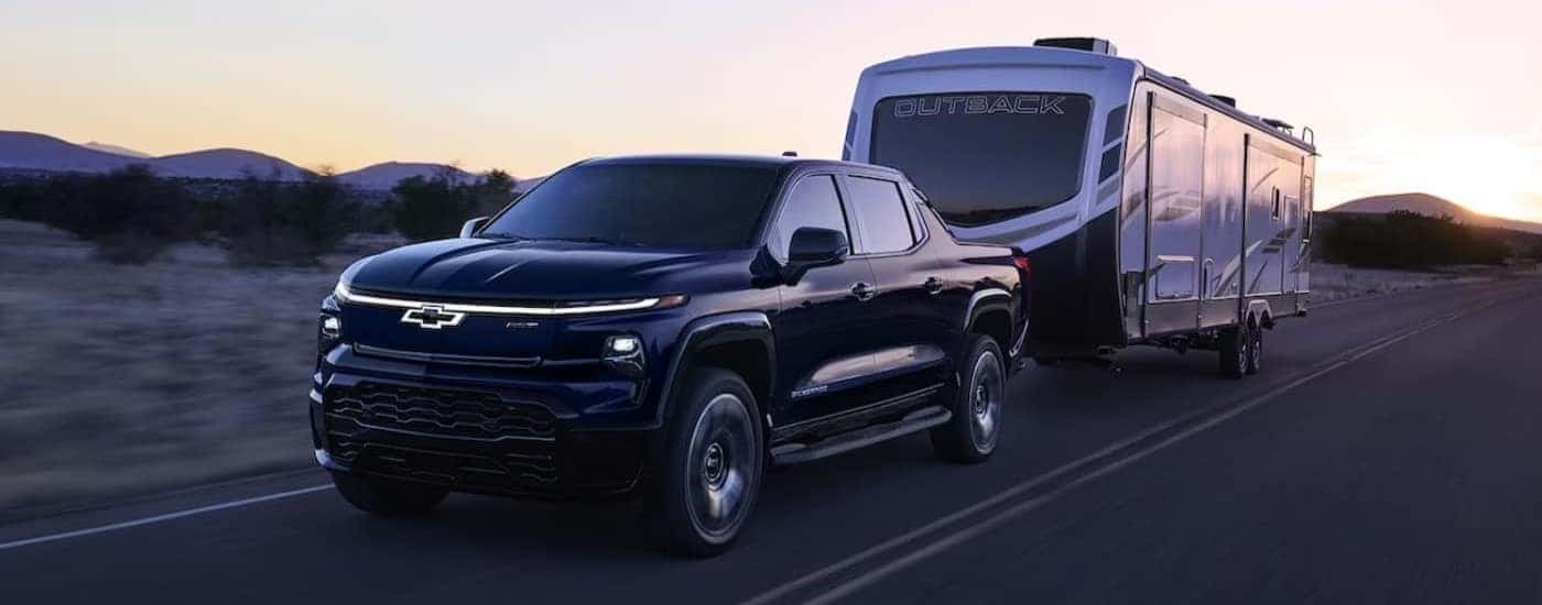 A black 2024 Chevy Silverado EV RST is shown towing a trailer.