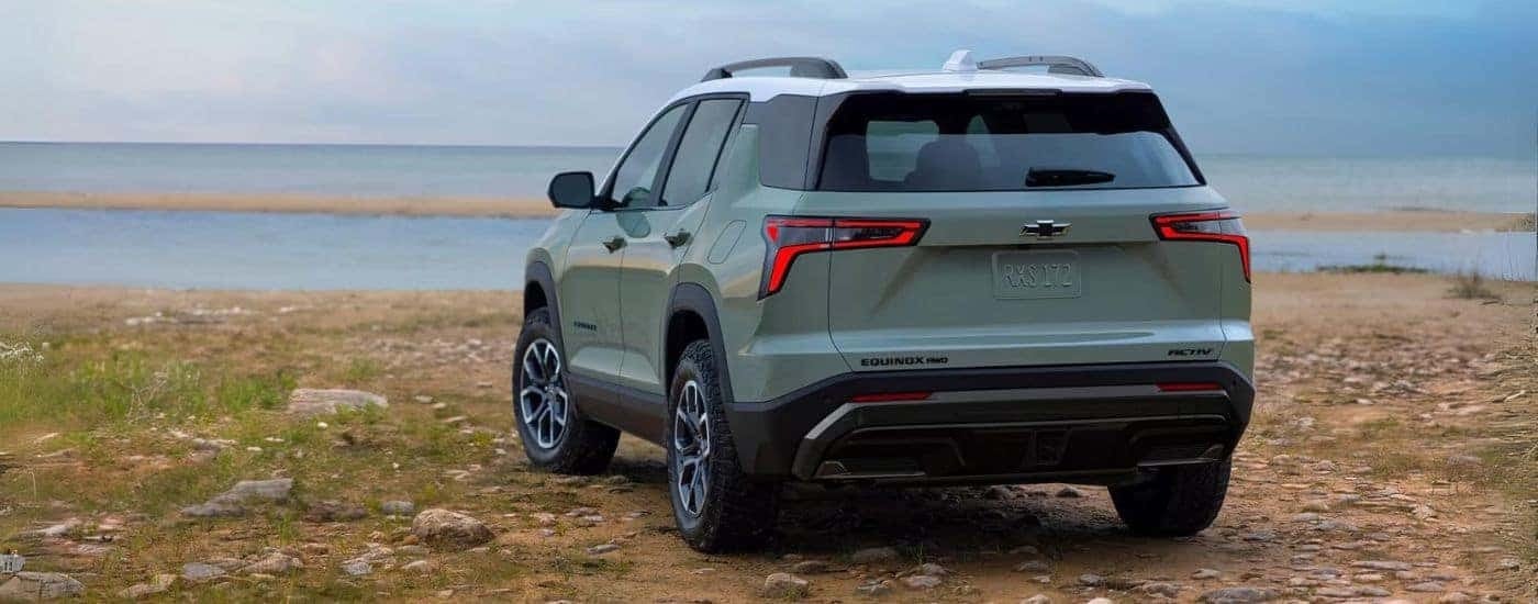 Rear of a green 2025 Chevy Equinox ACTIV parked by a lake.