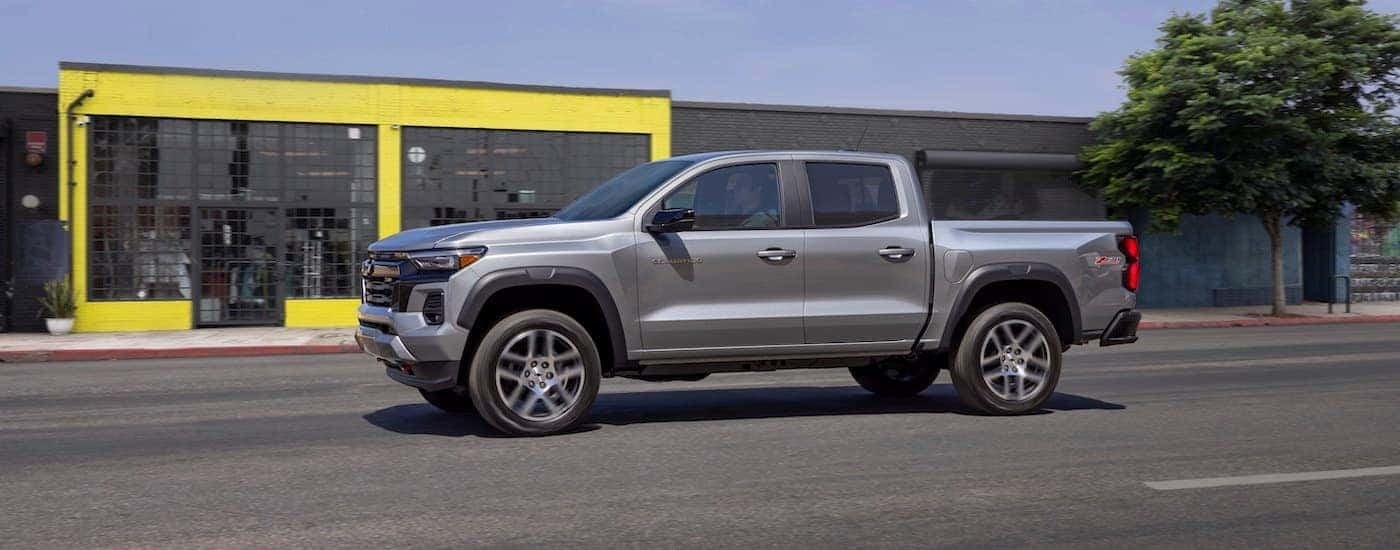 A grey 2023 Chevy Colorado Z71 is shown driving on a city street.