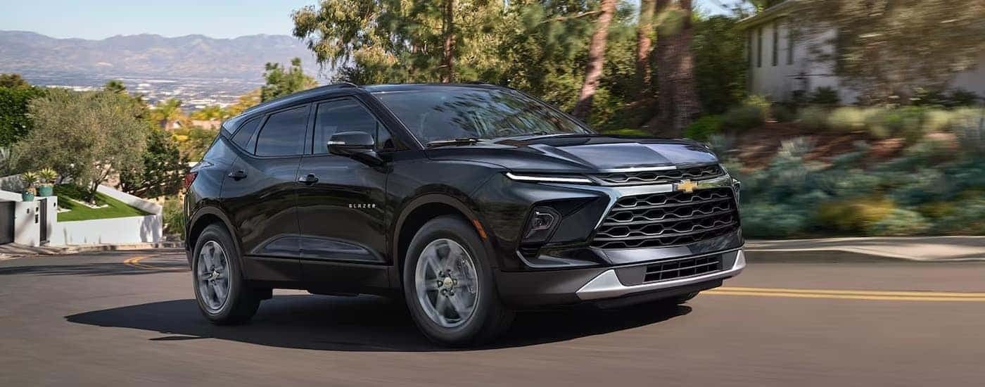 A black 2025 Chevy Blazer is driving on a winding city street