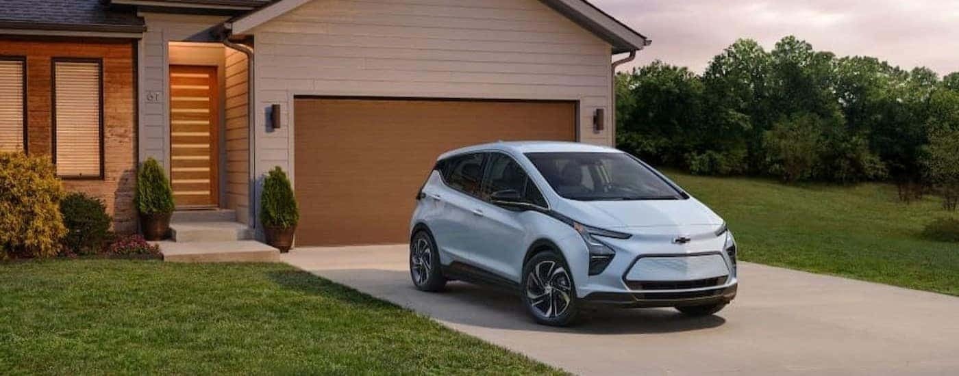 A light blue 2023 Chevy Bolt EV is shown parked on a driveway.