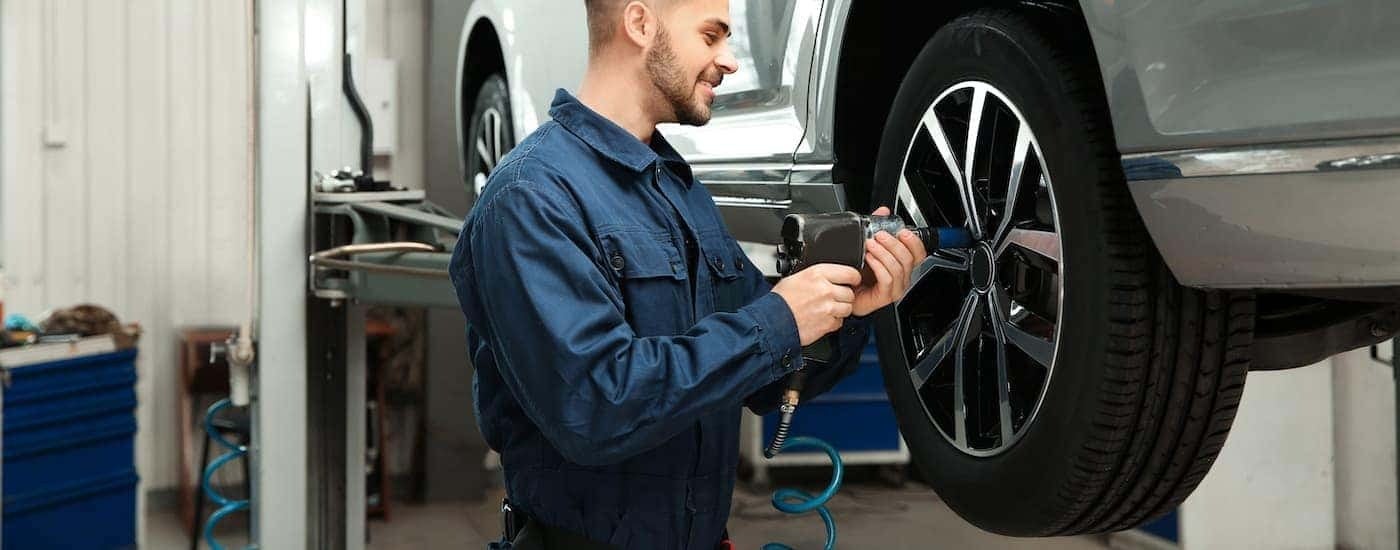 A technician is shown installing a wheel on a vehicle on a lift.