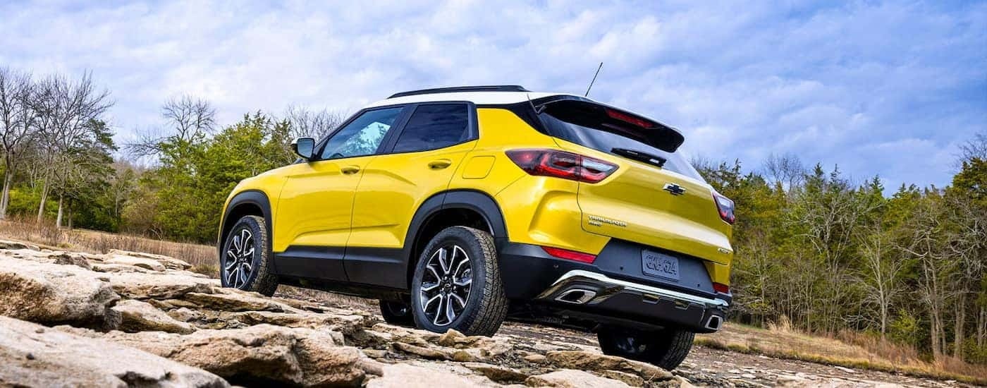 Rear view of a yellow 2025 Chevy Trailblazer ACTIV off-roading up a rocky hill.