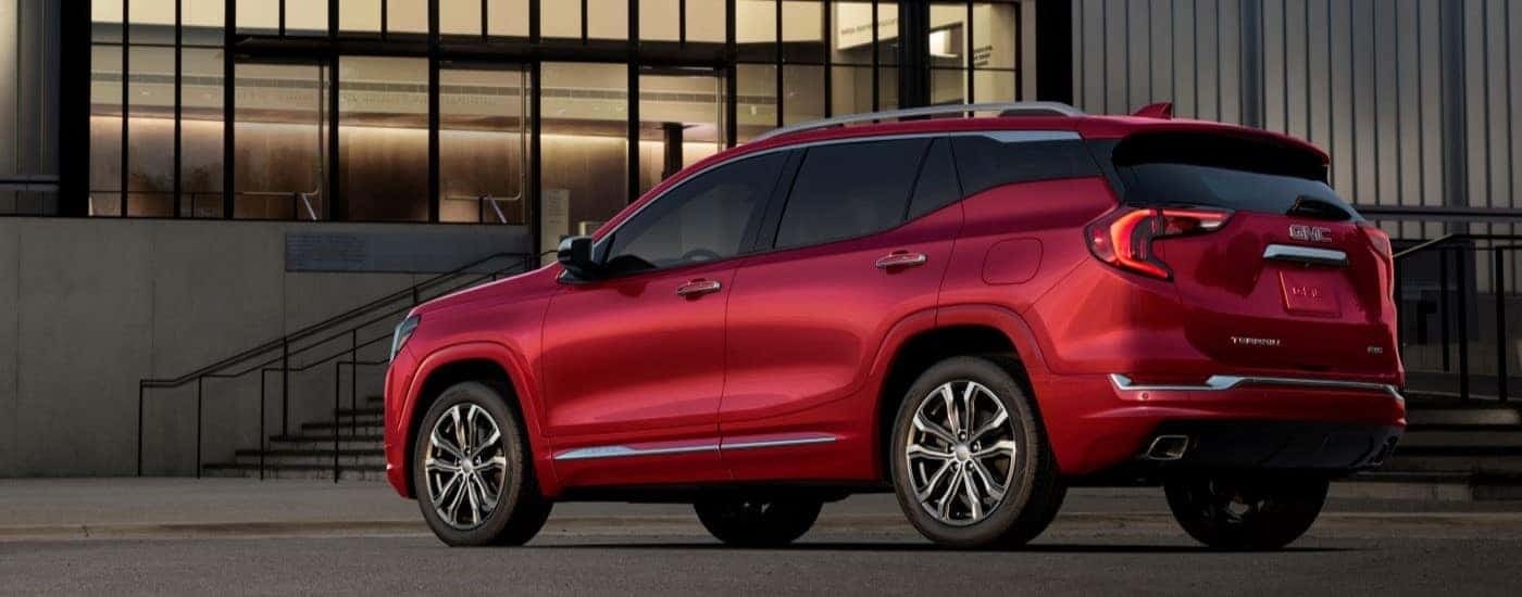 A red 2018 GMC Terrain Denali is shown in front of a modern building after looking at used SUVs for sale.