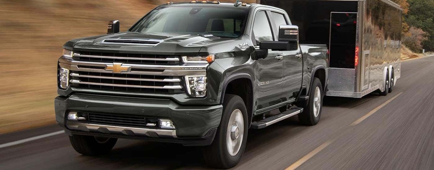 A black 2022 Chevy Silverado 2500 HD High Country is shown towing a large enclosed trailer.