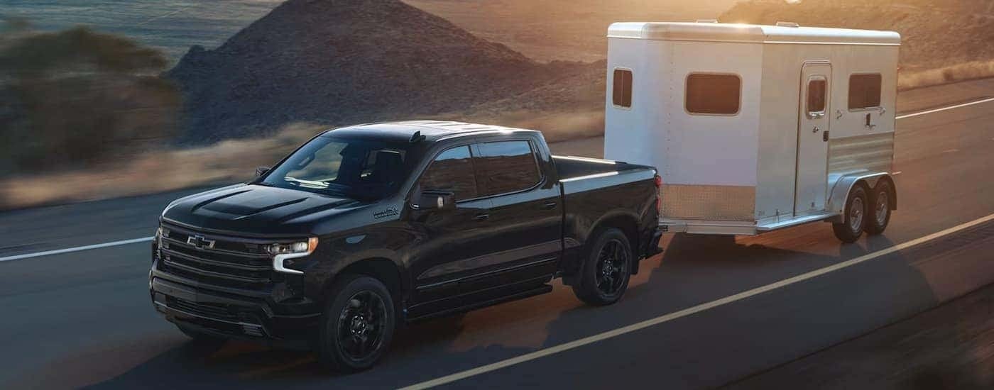 A black 2026 Chevy Silverado 1500 towing a horse trailer